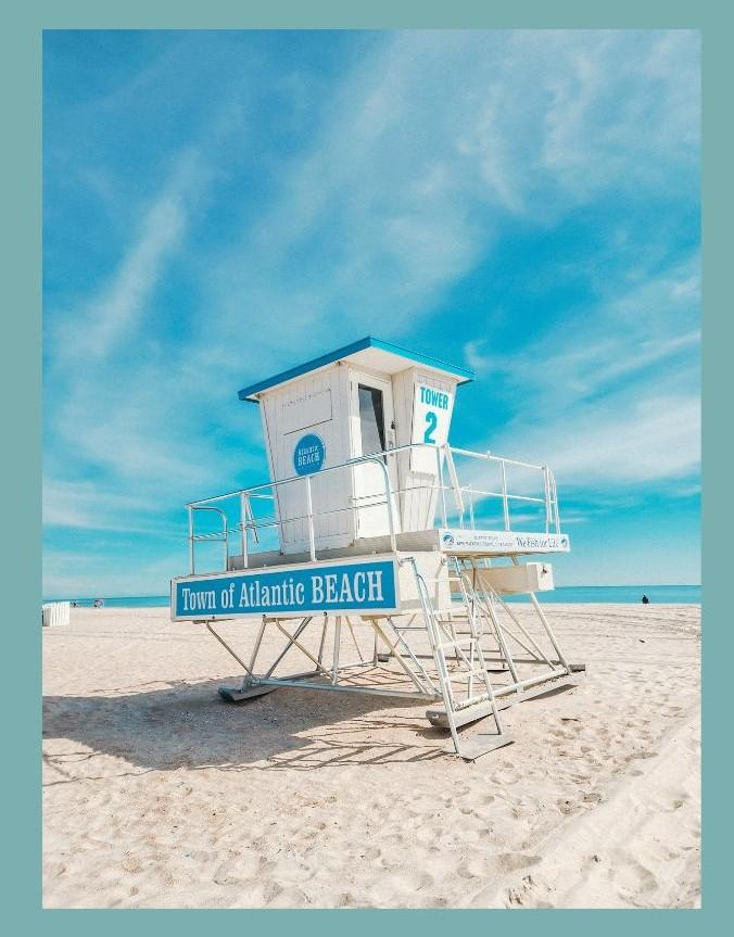 Town of Atlantic Beach lifeguard Tower 2 on white sand beach under bright blue sky