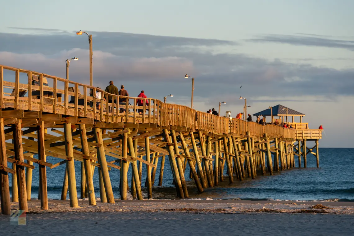 Atlantic Beach NC fishing pier at golden hour with people walking and fishing at sunset