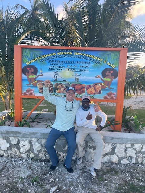 Two guys posing in front of Shine's Conch Shack Restaurant and Bar sign Andros Bahamas