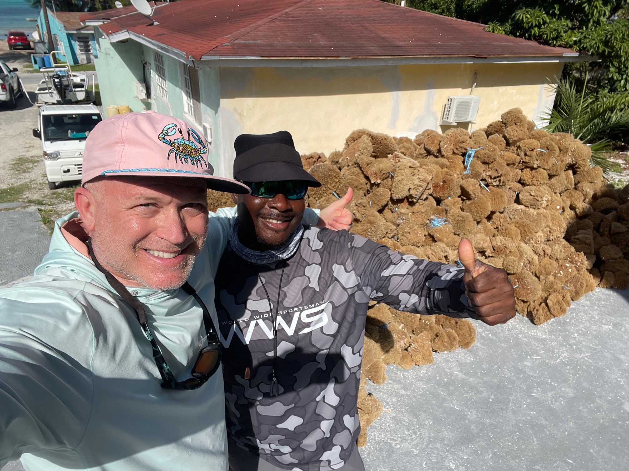 Two anglers holding a massive brain coral on the docks at Andros Bahamas thumbs up